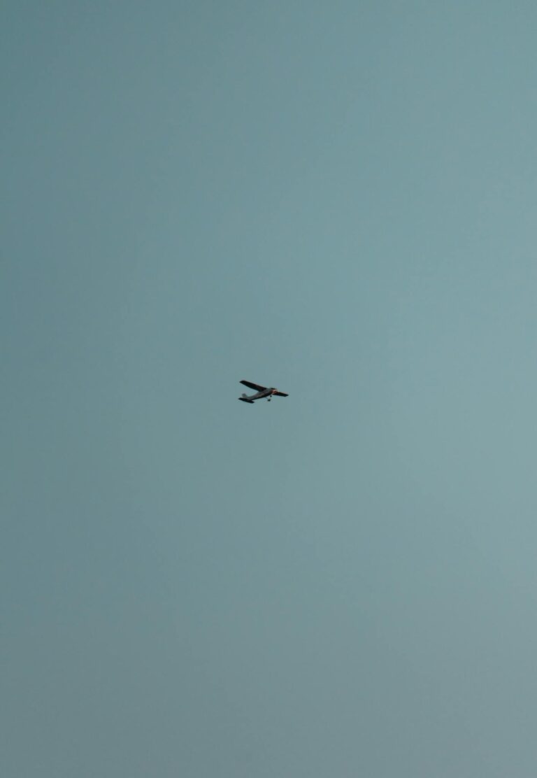A small aircraft flying amidst a clear blue sky, symbolizing freedom and adventure.